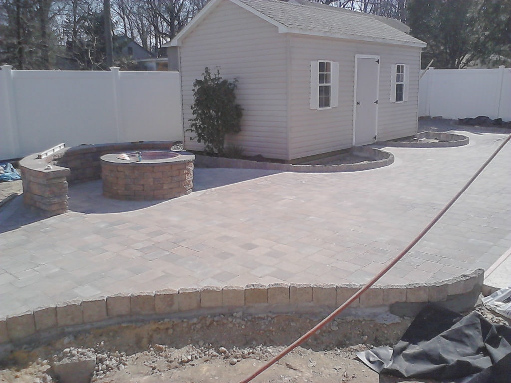A completed custom patio with fire pit by Custom Quality Renovations.